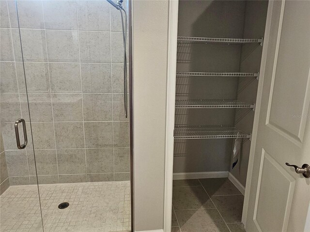 3776 Maxwell Park Dr, Sun City Center, FL 33573 - bathroom with a stall shower, tile patterned floors, a spacious closet, and baseboards