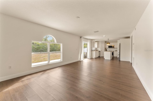 unfurnished living room with dark wood-style flooring, baseboards, and healthy amount of natural light