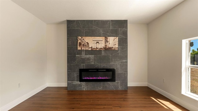 detailed view of wood finished floors, a tiled fireplace, and baseboards