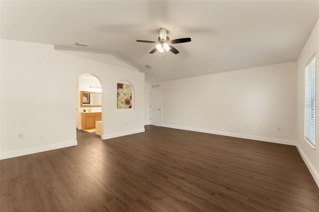 unfurnished living room with a ceiling fan, dark wood-style floors, baseboards, lofted ceiling, and arched walkways