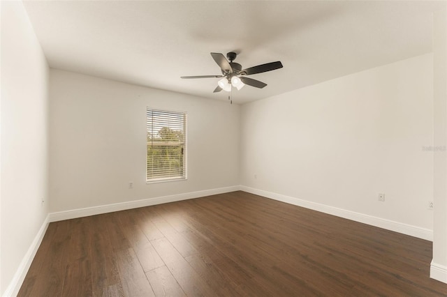 spare room featuring a ceiling fan, dark wood-type flooring, and baseboards