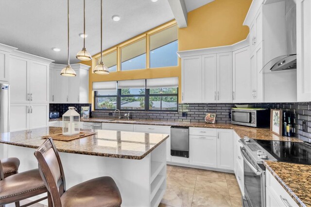 2287 Demaret Dr, Dunedin, FL 34698 - kitchen with stainless steel appliances, wall chimney range hood, a kitchen bar, white cabinets, and recessed lighting