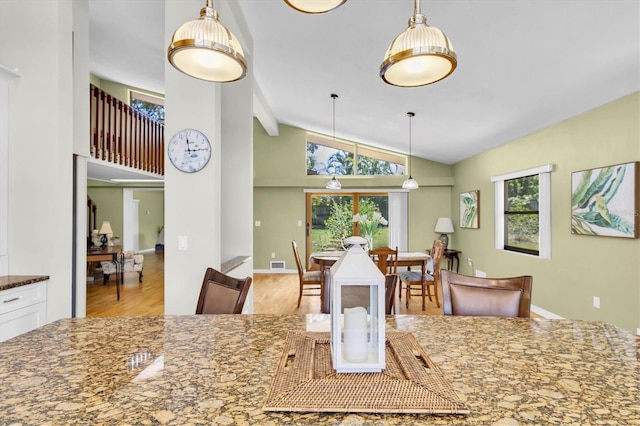 2287 Demaret Dr, Dunedin, FL 34698 - kitchen with wood finished floors, dark stone counters, pendant lighting, white cabinetry, and high vaulted ceiling