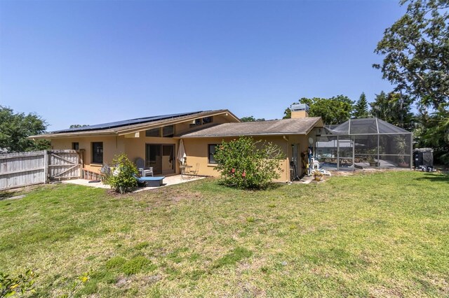 2287 Demaret Dr, Dunedin, FL 34698 - rear view of property with roof mounted solar panels, a chimney, a patio, a gate, and stucco siding
