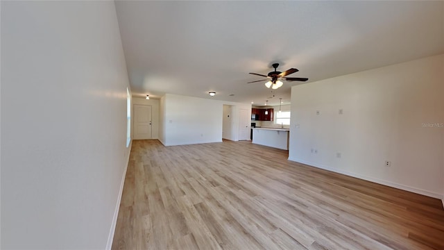 unfurnished living room featuring a ceiling fan, light wood-style flooring, and baseboards