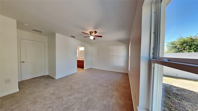 spare room with light colored carpet, a ceiling fan, and baseboards