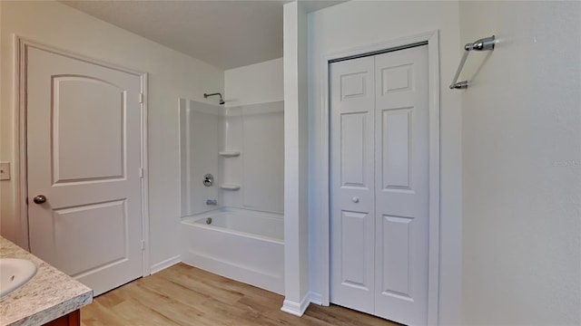 bathroom with wood finished floors, vanity, shower / bath combination, baseboards, and a closet