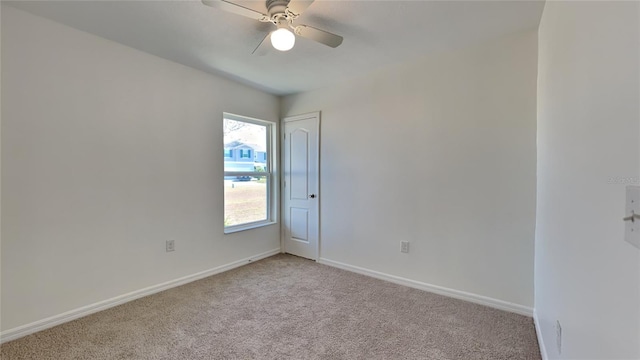 empty room with light colored carpet, ceiling fan, and baseboards