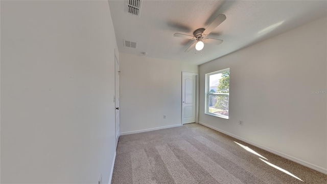 unfurnished room with baseboards, ceiling fan, and light colored carpet