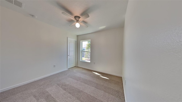 empty room featuring a ceiling fan, light colored carpet, baseboards, and a smoke detector