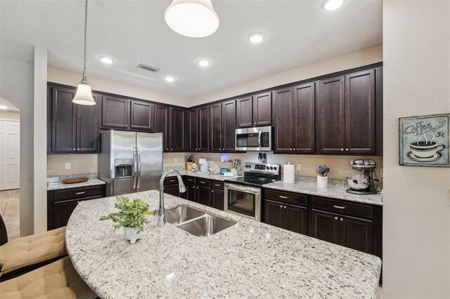 9917 Prevatt St, Gibsonton, FL 33534 - kitchen featuring stainless steel appliances, a sink, dark brown cabinets, an island with sink, and arched walkways