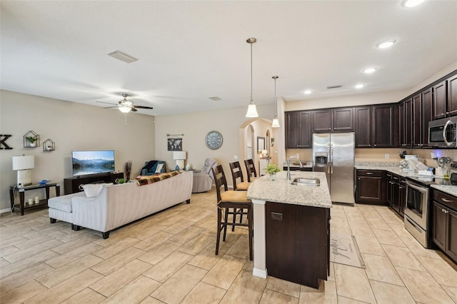 9917 Prevatt St, Gibsonton, FL 33534 - kitchen with appliances with stainless steel finishes, arched walkways, a sink, open floor plan, and dark brown cabinetry