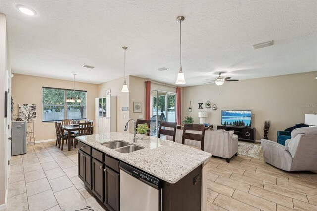 9917 Prevatt St, Gibsonton, FL 33534 - kitchen featuring a sink, dishwasher, open floor plan, light stone counters, and a kitchen island with sink