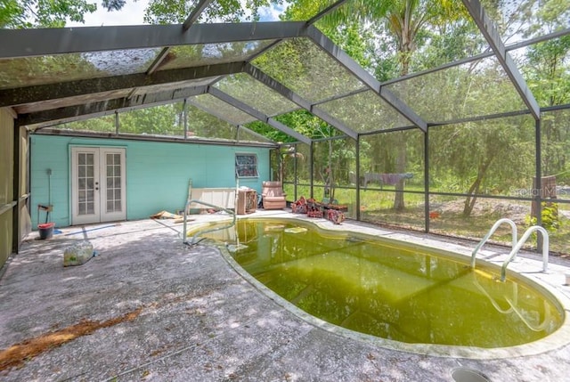 swimming pool with french doors, a patio area, and glass enclosure