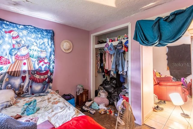 bedroom with a textured ceiling, a closet, and tile patterned flooring