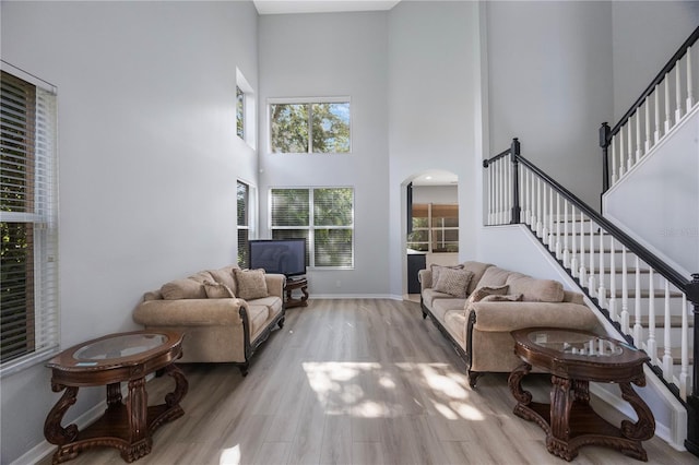 17809 Sandpine Trace Way, Tampa, FL 33647 - living area featuring a towering ceiling, arched walkways, stairway, light wood-style flooring, and baseboards