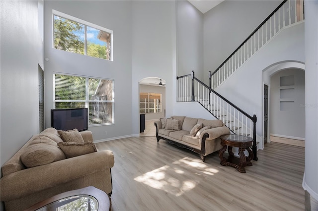 17809 Sandpine Trace Way, Tampa, FL 33647 - living room featuring arched walkways, a towering ceiling, light wood finished floors, baseboards, and a ceiling fan