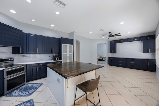 17809 Sandpine Trace Way, Tampa, FL 33647 - kitchen featuring range with two ovens, arched walkways, backsplash, light tile patterned floors, and a ceiling fan