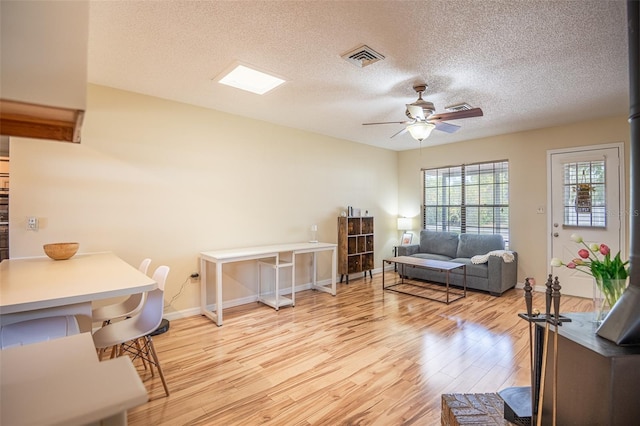 living area featuring wood finished floors, ceiling fan, a textured ceiling, and baseboards