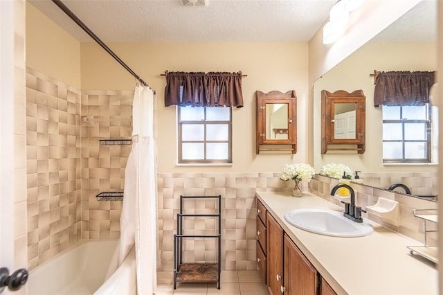bathroom with plenty of natural light, tile walls, a textured ceiling, tile patterned floors, and vanity