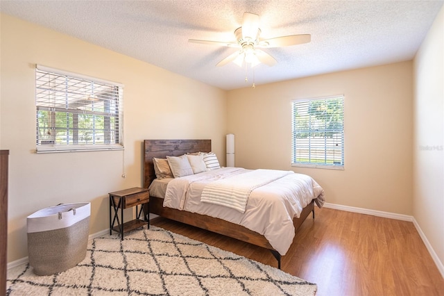 bedroom featuring light wood finished floors, baseboards, a textured ceiling, and ceiling fan