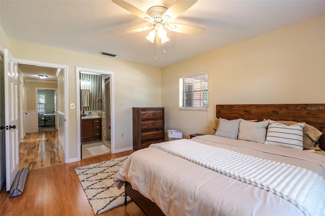 bedroom featuring light wood finished floors, ceiling fan, and ensuite bathroom