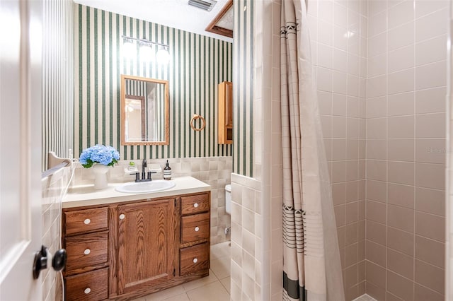 full bath with wallpapered walls, a shower stall, vanity, tile patterned flooring, and tile walls
