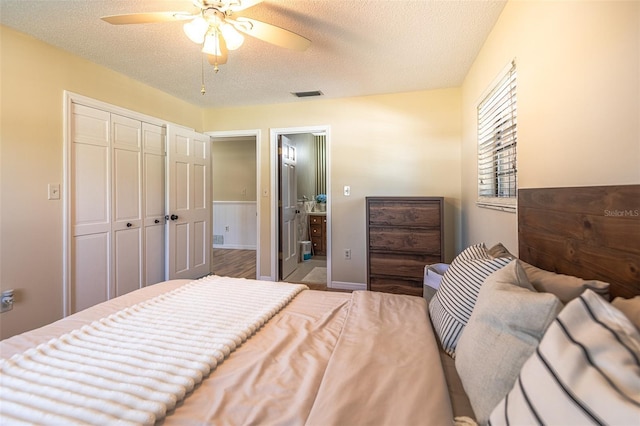 bedroom with a textured ceiling, a closet, ensuite bathroom, and a ceiling fan