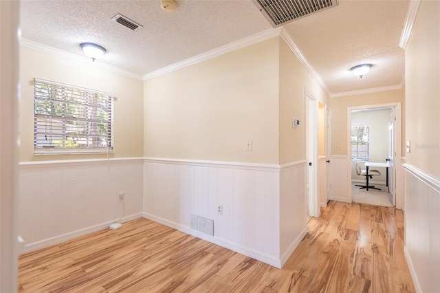 unfurnished room featuring a textured ceiling, wood finished floors, wainscoting, ornamental molding, and a smoke detector