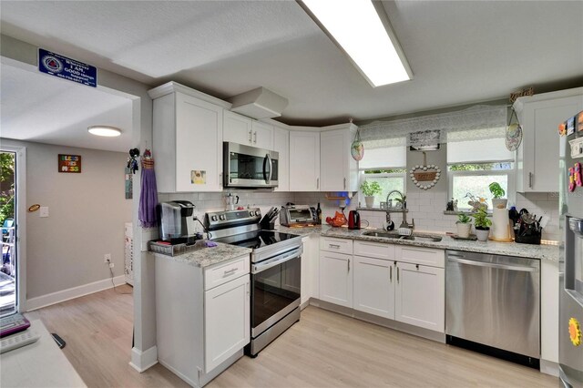528 S Seminole Ave, Fort Meade, FL 33841 - kitchen featuring appliances with stainless steel finishes, a sink, light wood finished floors, and decorative backsplash