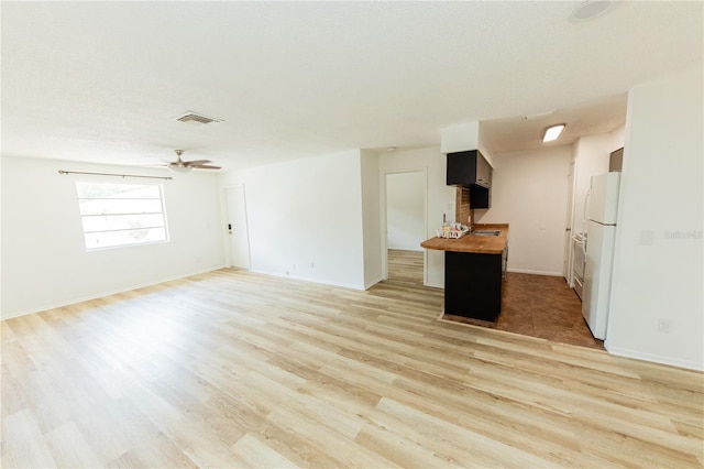 unfurnished living room featuring light wood-type flooring, baseboards, and a ceiling fan