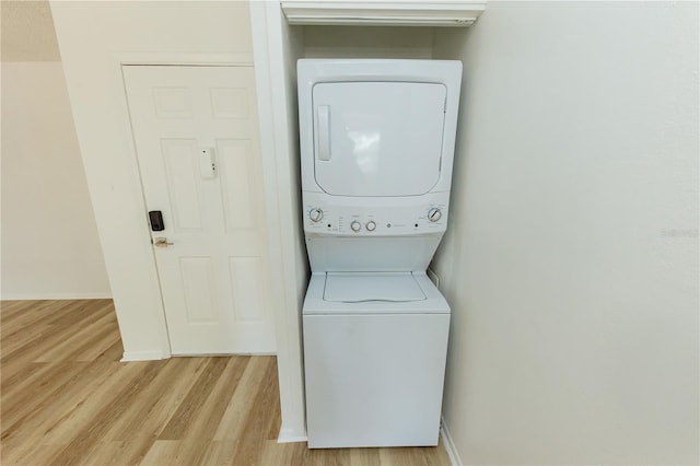 laundry area with estacked washer and dryer, light wood-style flooring, and baseboards