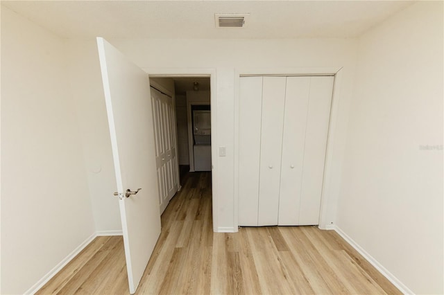 unfurnished bedroom with light wood-style floors, baseboards, and a closet