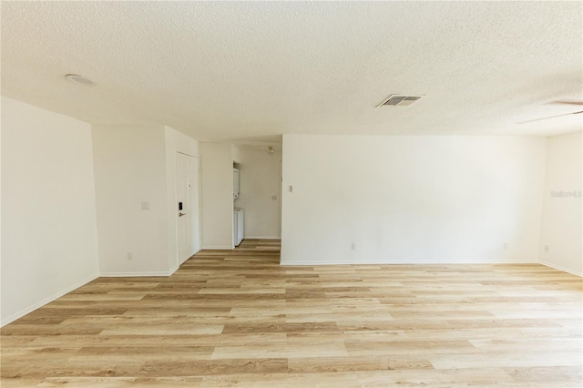 spare room with a textured ceiling, light wood finished floors, and baseboards