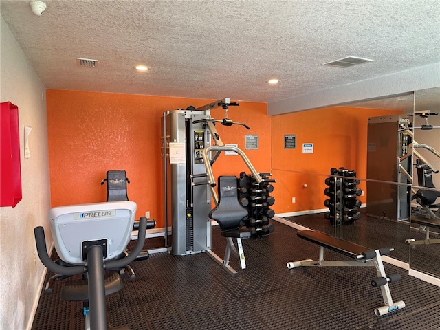 exercise room featuring a textured ceiling, a textured wall, recessed lighting, and baseboards