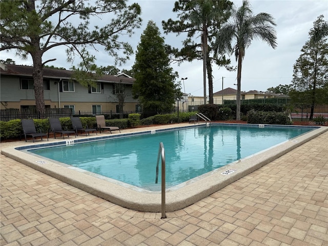 community pool with fence and a patio area