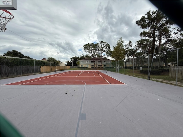 view of basketball court featuring a tennis court, community basketball court, and fence