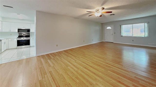unfurnished living room featuring light wood-style flooring, ceiling fan, a textured ceiling, and baseboards