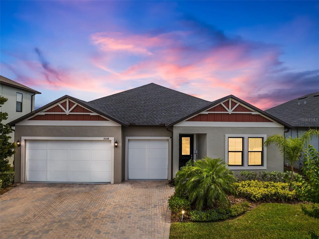21648 Snowy Orchid Ter, Land O Lakes, FL 34637 - view of front of property featuring decorative driveway, an attached garage, a shingled roof, and stucco siding