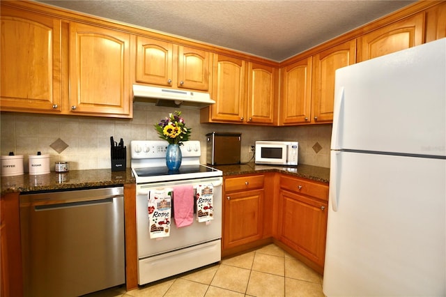 6150 Gulfport Blvd S Unit 302, Gulfport, FL 33707 - kitchen featuring white appliances, under cabinet range hood, light tile patterned flooring, backsplash, and brown cabinetry