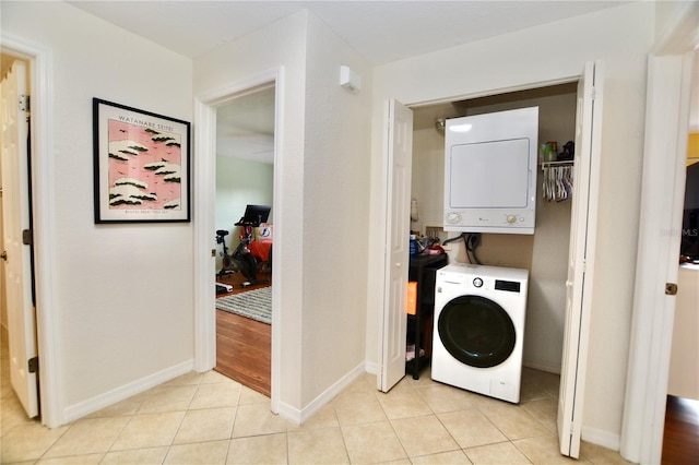 6150 Gulfport Blvd S Unit 302, Gulfport, FL 33707 - laundry area featuring stacked washing machine and dryer, baseboards, and light tile patterned floors