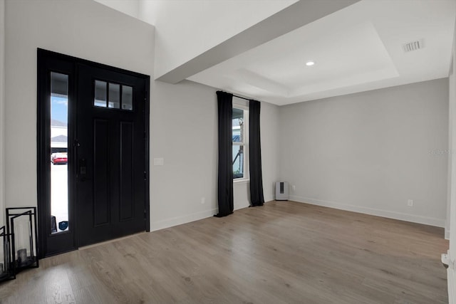 entryway featuring a raised ceiling, wood finished floors, and baseboards