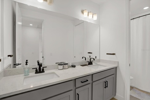 bathroom with double vanity, toilet, and recessed lighting