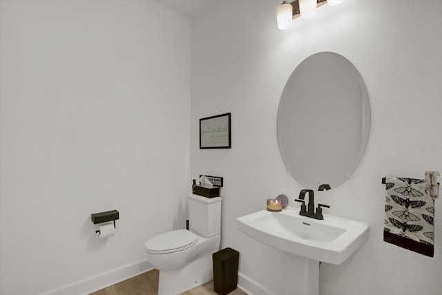 bathroom featuring toilet, wood finished floors, and baseboards