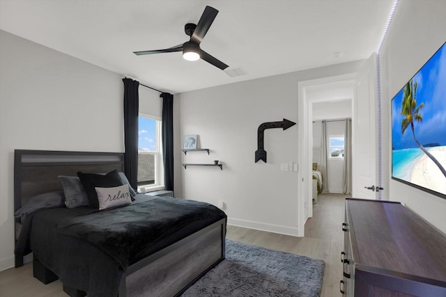 bedroom with light wood-type flooring, a ceiling fan, and baseboards