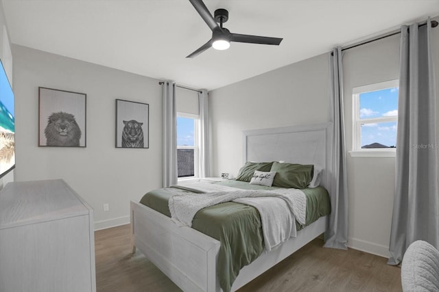 bedroom featuring multiple windows, wood finished floors, and baseboards