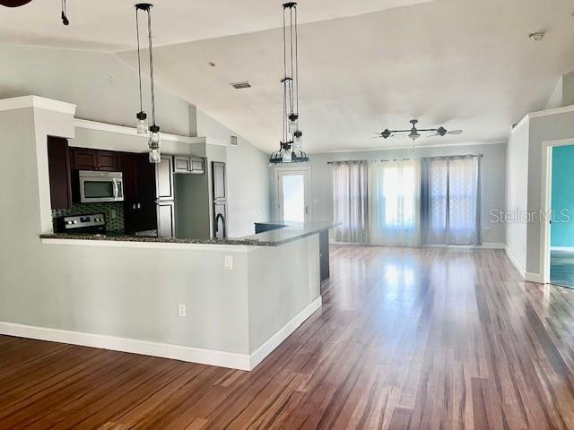 kitchen featuring stainless steel appliances, a ceiling fan, wood finished floors, open floor plan, and lofted ceiling