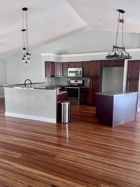 kitchen featuring stainless steel appliances, vaulted ceiling, dark wood-style flooring, decorative backsplash, and pendant lighting