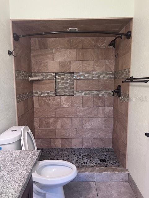 bathroom with toilet, a stall shower, and vanity