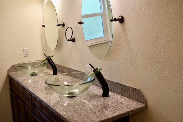 bathroom featuring a textured wall and double vanity